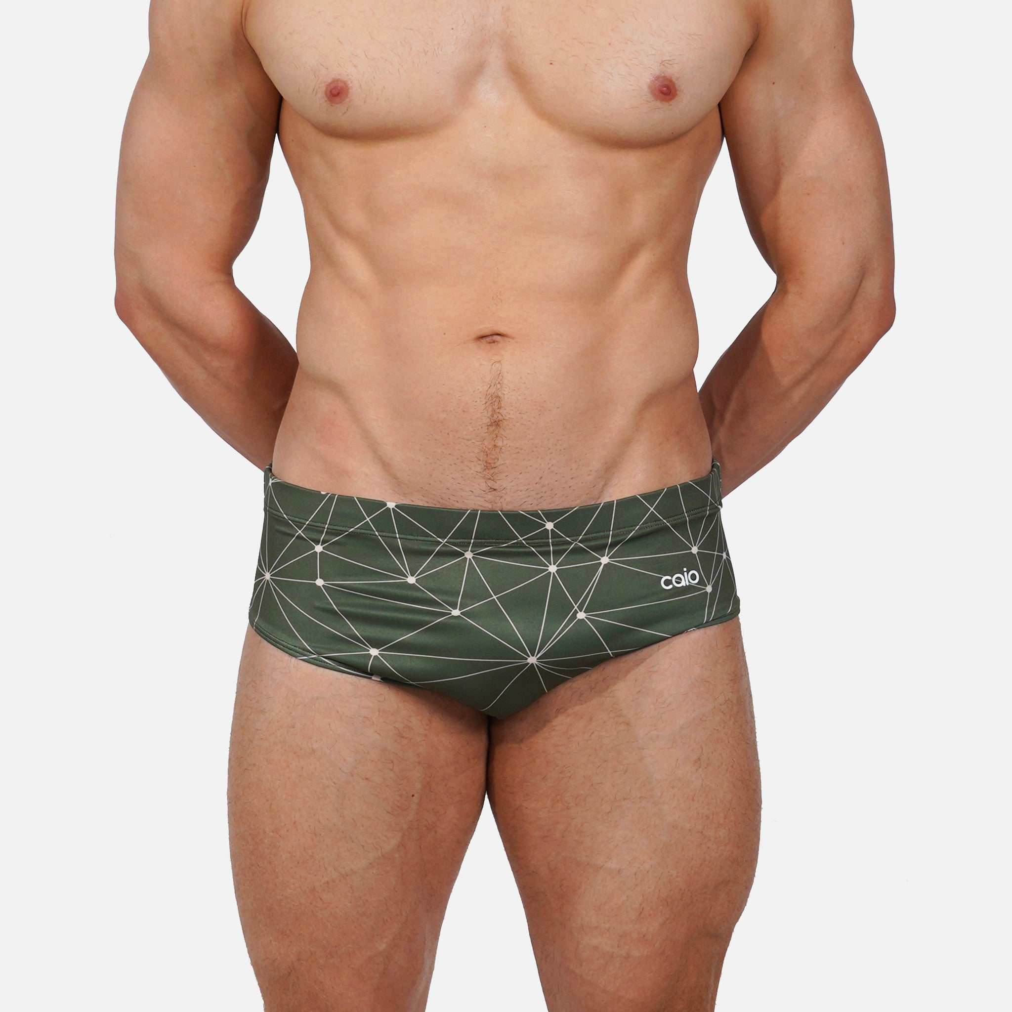 Man wearing green swim briefs with geometric pattern on a white background