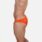 Model wearing Bikini Caio Brazilian swim brief in Solar Flare (orange)