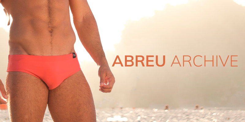 Person wearing red swim trunks on a beach with 'ABREU ARCHIVE' branding.