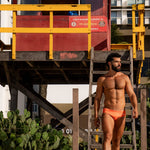 Model wearing Slim Caio Brazilian swim brief in Solar Flare (orange)