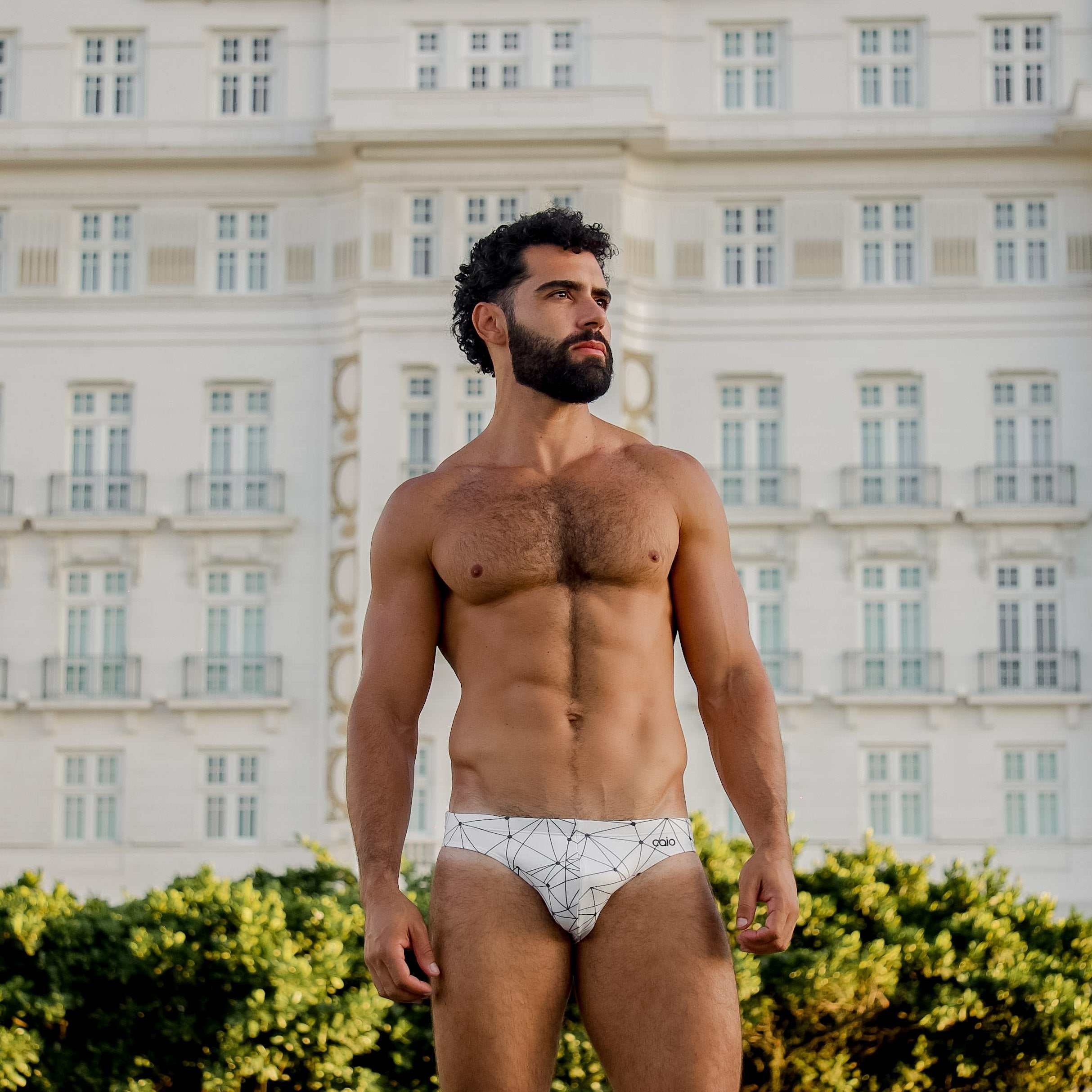 Model wearing Bikini Caio Brazilian swim brief in Nova Frost (white) outside Copacabana Palace.