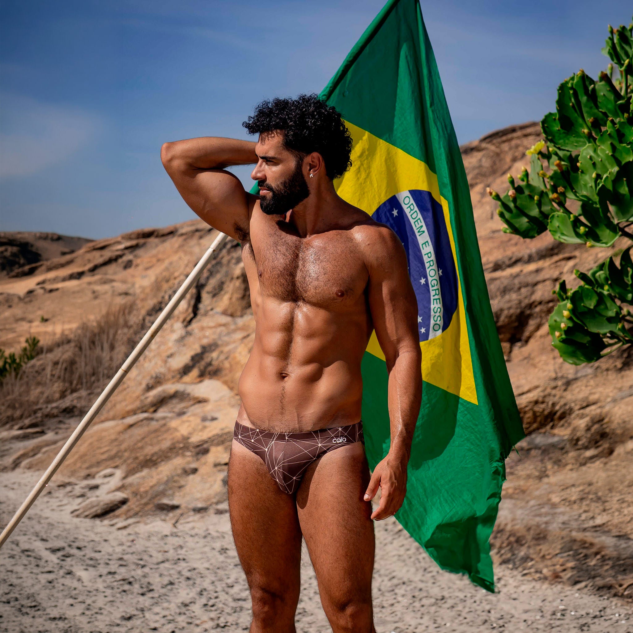 Model wearing caio bikini Astral Soil swim brief holding brazilian flag